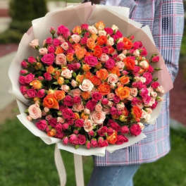 Large bouquet of multicolored spray roses wrapped in white paper