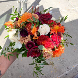 Handheld bouquet of red, orange, white, and purple flowers