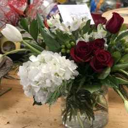 Bouquet of red roses, white hydrangea, and white tulips in a glass vase