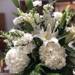 White lilies and hydrangeas arranged with green foliage