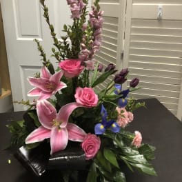 Pink lilies, roses, and purple flowers in a low black wrap