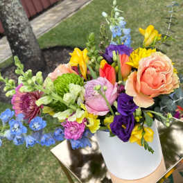 Colorful mixed bouquet in a white vase on a gold stand.