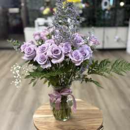Lavender roses in a glass vase with purple filler flowers