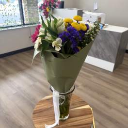 Mixed bouquet of white, purple, yellow, and pink flowers in a glass vase