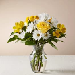 Yellow and white flowers arranged in a clear glass vase