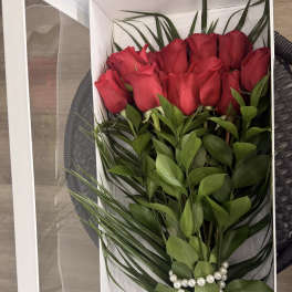 Red roses arranged in a white gift box with pearl accents
