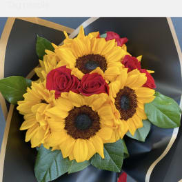 Bouquet of yellow sunflowers and red roses wrapped in black paper