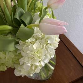 Pink tulips arranged with white hydrangeas in a glass vase