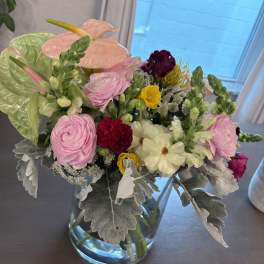 Mixed bouquet in a clear glass vase with pink, white, and yellow blooms