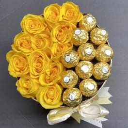 Yellow roses arranged with gold-wrapped chocolates in a round bouquet