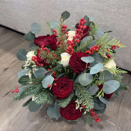 Bouquet of red roses with white blooms, berries, and evergreen foliage