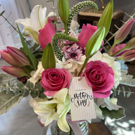 Bouquet of pink roses and white lilies in a glass vase with a Mother's Day tag