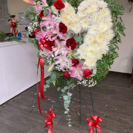 Heart-shaped floral standing spray with red roses, pink lilies, and white chrysanthemums