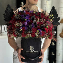 Large bouquet of red and purple flowers in a black box with black feathers.