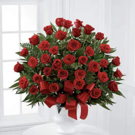 Red rose arrangement in a white vase with a red ribbon