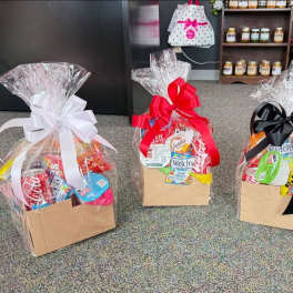 Three wrapped gift baskets filled with snacks and soda
