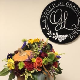 Autumn floral arrangement in a pumpkin container with mixed blooms