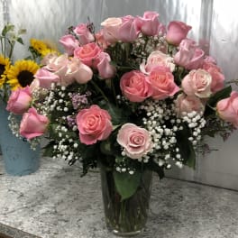 Pink roses in a clear glass vase with baby's breath