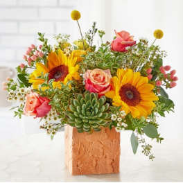 Mixed bouquet with sunflowers, roses, and a succulent in a textured square vase