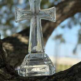 Clear glass cross ornament on a tree branch