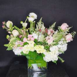 Pink and white floral arrangement in a square glass vase