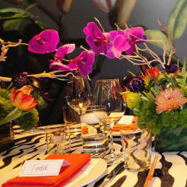 Bright orchid centerpiece with orange and purple flowers on a zebra-print table