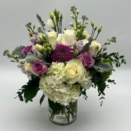 Bouquet of cream and purple flowers in a clear glass vase