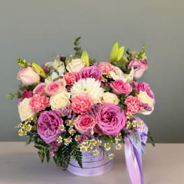 Mixed pink and cream flower arrangement in a lavender hat box with ribbon