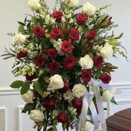Standing spray of red and white roses with ribbon on an easel