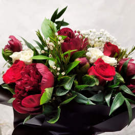 Bouquet of red and white flowers wrapped in black paper with a red ribbon
