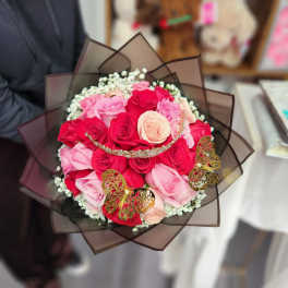 Bouquet of pink and red roses wrapped in dark brown paper with butterfly accents
