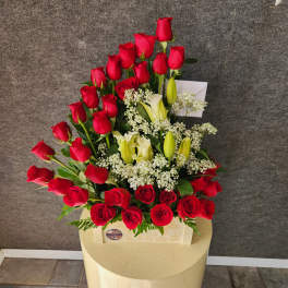 Red roses and white lilies arranged in a cream box