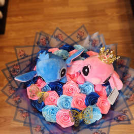 Bouquet of blue and pink roses with two plush characters and butterfly wrap