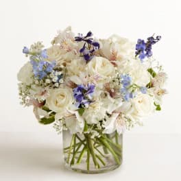 White and blue mixed bouquet in a clear glass vase