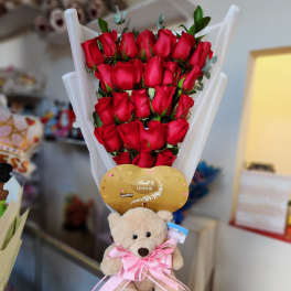 Bouquet of red roses with a teddy bear and chocolate gift topper