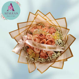 Peach rose bouquet wrapped in tan-edged paper with a ribbon