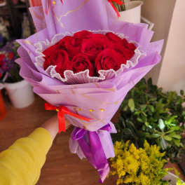 Bouquet of red roses wrapped in lavender paper with red ribbons