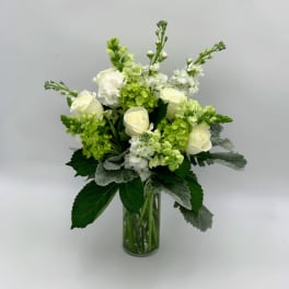 White roses and green blooms in a clear glass vase