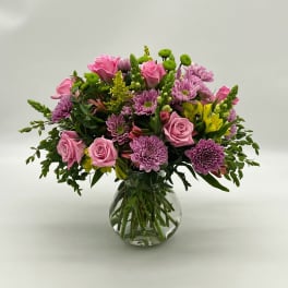 Pink roses and purple chrysanthemums in a clear glass vase