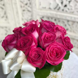 Bouquet of bright pink roses with a white ribbon bow