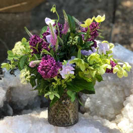 Mixed bouquet in a textured glass vase with purple, lavender, and yellow blooms