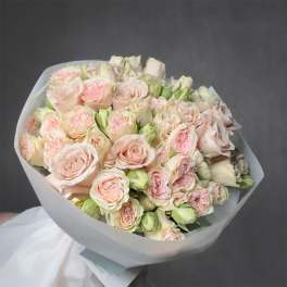 Hand-tied bouquet of blush and peach roses wrapped in white paper