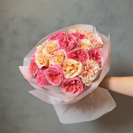 Bouquet of pink and peach roses wrapped in pale paper