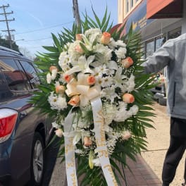 Large standing floral spray with white flowers and peach roses on an easel