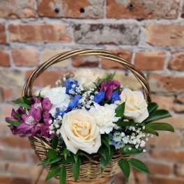 Basket arrangement with cream roses, purple blooms, and blue flowers