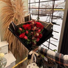 Bouquet of red roses and pink tulips wrapped in black paper