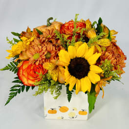 Autumn bouquet of sunflowers, roses, and mums in a pumpkin-decorated box