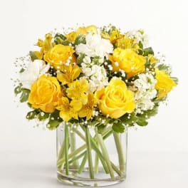 Yellow and white flower bouquet in a clear glass vase