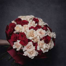 Large round bouquet of red and cream roses wrapped in deep red paper