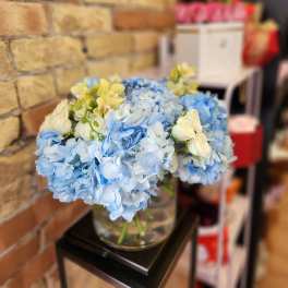 Blue hydrangea bouquet with white roses in a glass vase